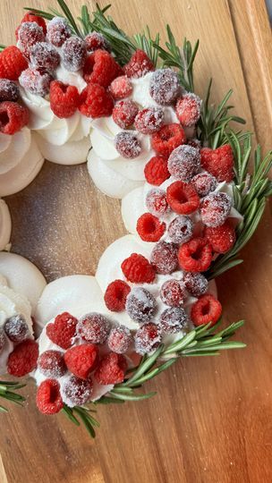 a christmas wreath made out of cookies and raspberries on a cutting board with rosemary sprigs