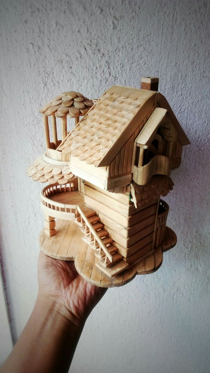 a hand holding a wooden model of a house