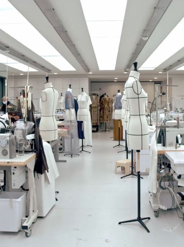 a room filled with lots of white mannequins and sewing machines in it