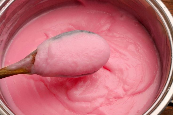 a spoon full of pink paste in a metal pot