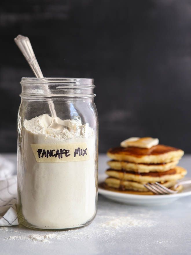 a glass jar filled with vanilla ice cream next to stack of pancakes on a plate