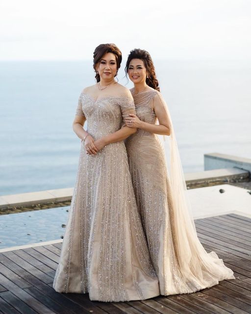 two women standing next to each other on top of a wooden deck near the ocean