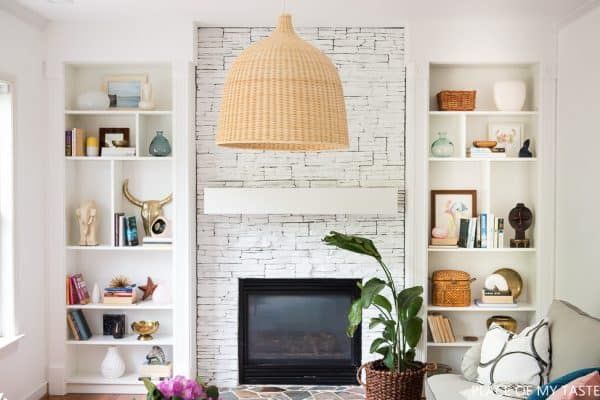 a living room filled with furniture and a fire place under a large light hanging from the ceiling