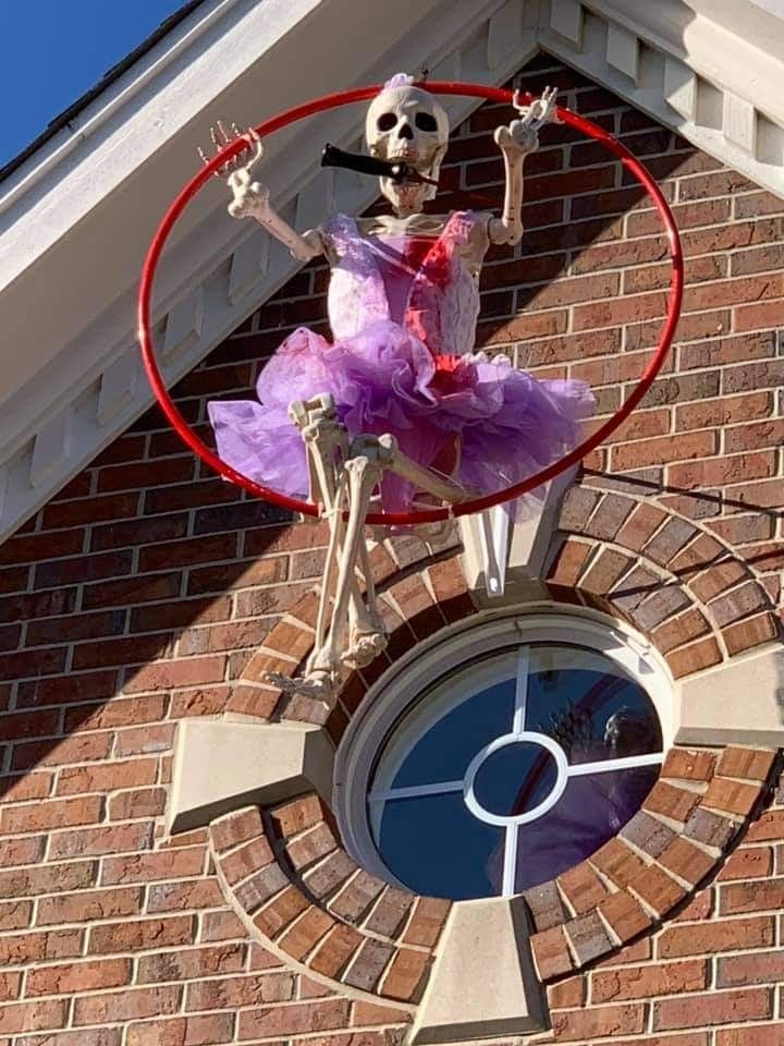 a skeleton in a purple dress is playing with a hoop on the side of a building