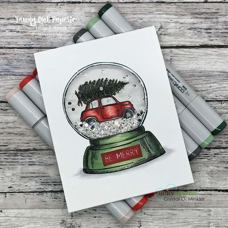 a snow globe with a red car in it sitting on top of some crayons