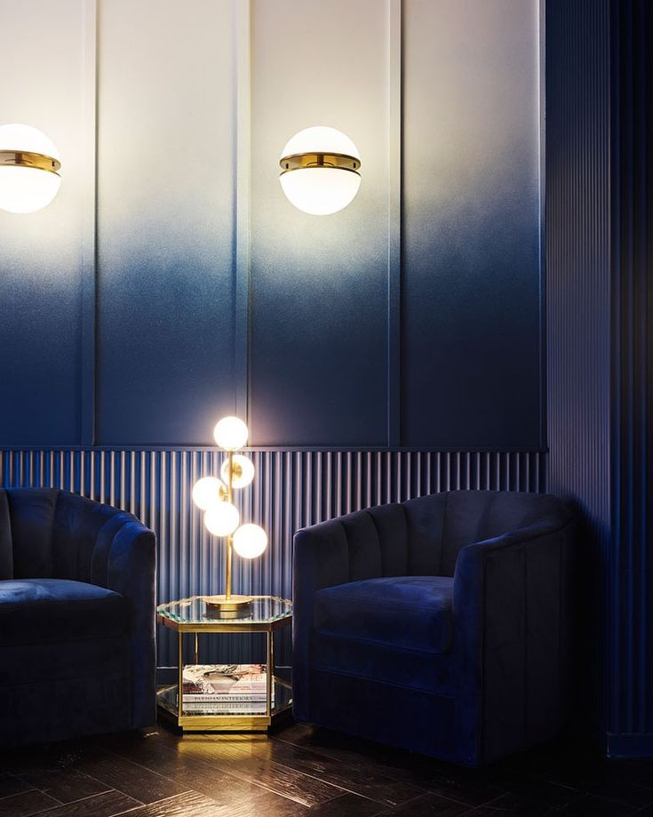 two chairs and a table in a room with blue walls, gold trim around them