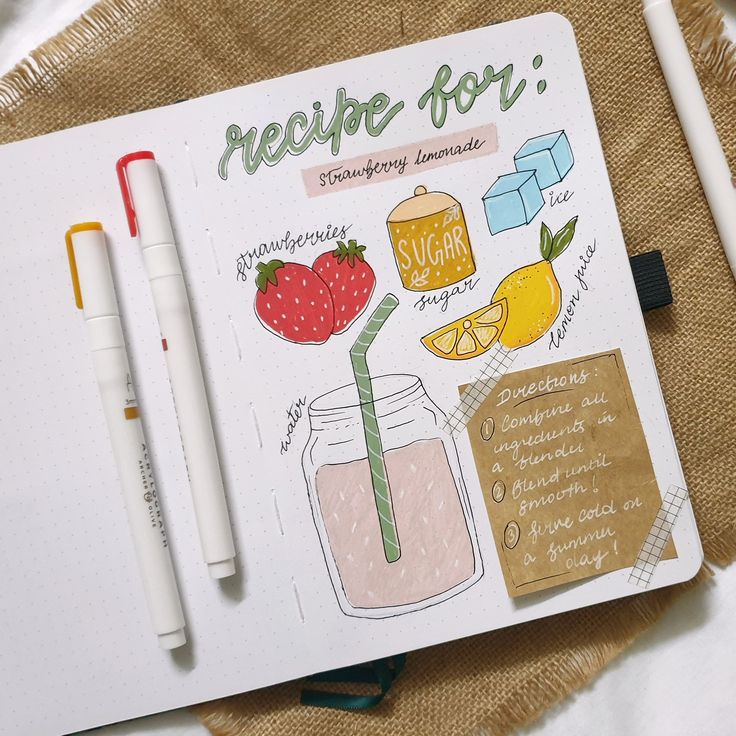 a recipe book with strawberries, oranges and lemonade on it next to a pen