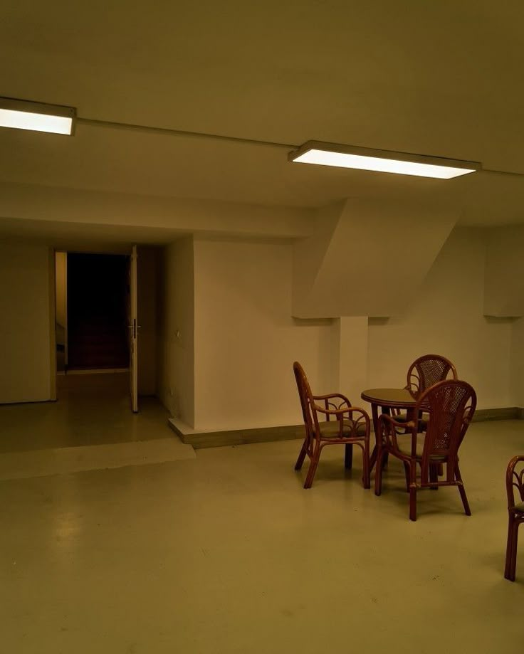 an empty room with several chairs and tables in it, all lit up by recessed lights