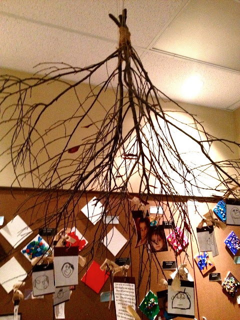 a tree branch hanging from the ceiling with many cards and magnets attached to it