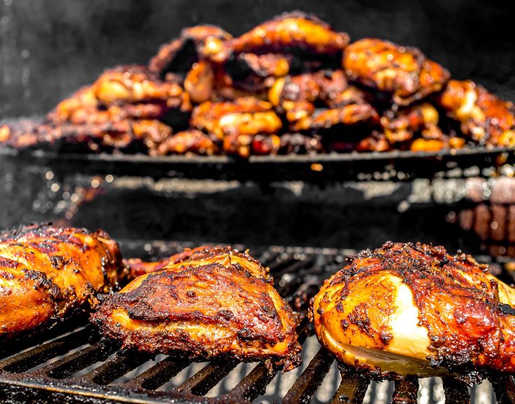 some chicken is cooking on a grill with other food items