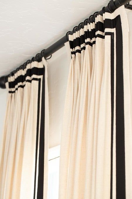 black and white striped curtains hanging on the side of a window with an open curtain rod