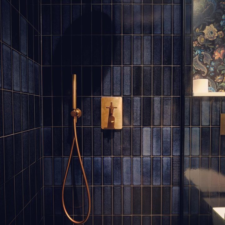 a bathroom with blue tiled walls and a gold faucet in the shower head