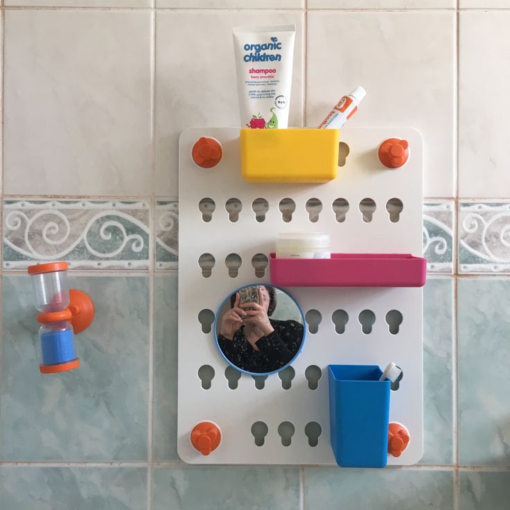 a person taking a selfie in front of a mirror on a tiled bathroom wall