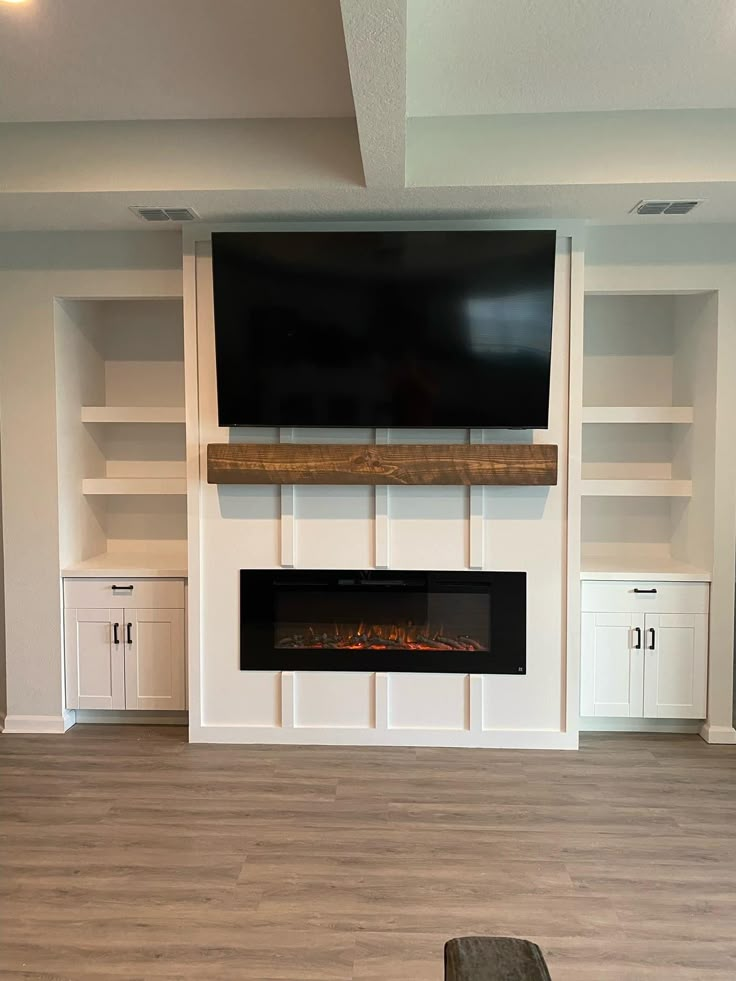 an empty living room with built - in fireplace and entertainment center