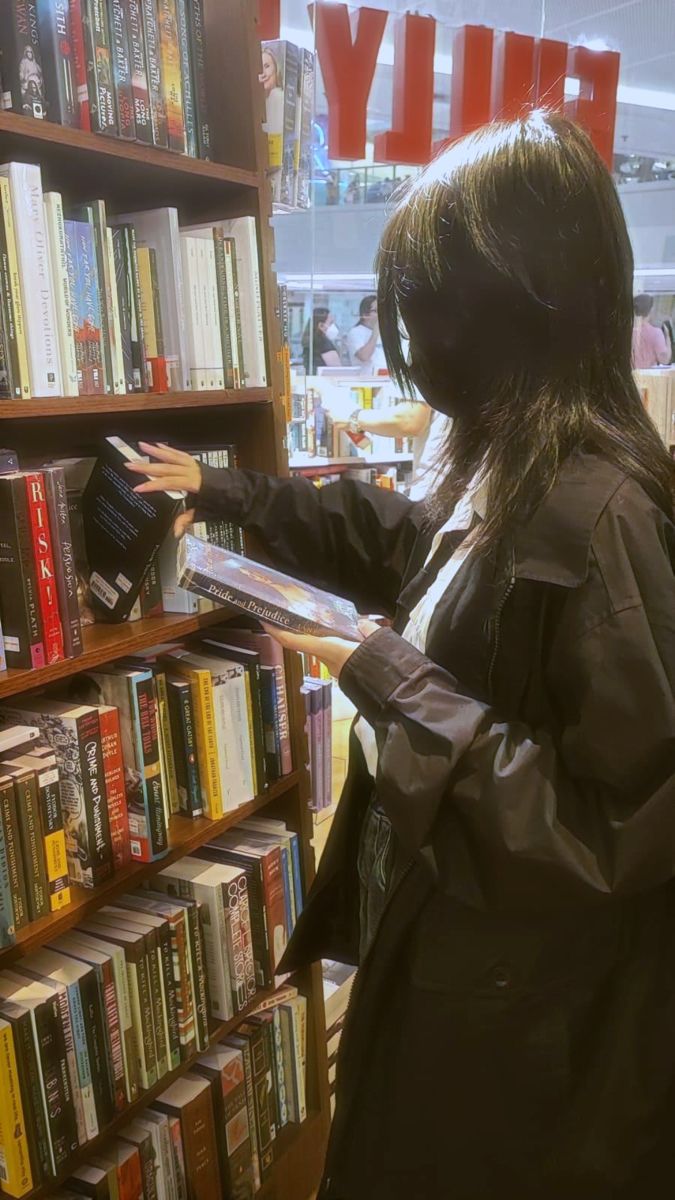 a woman standing in front of a book shelf filled with books