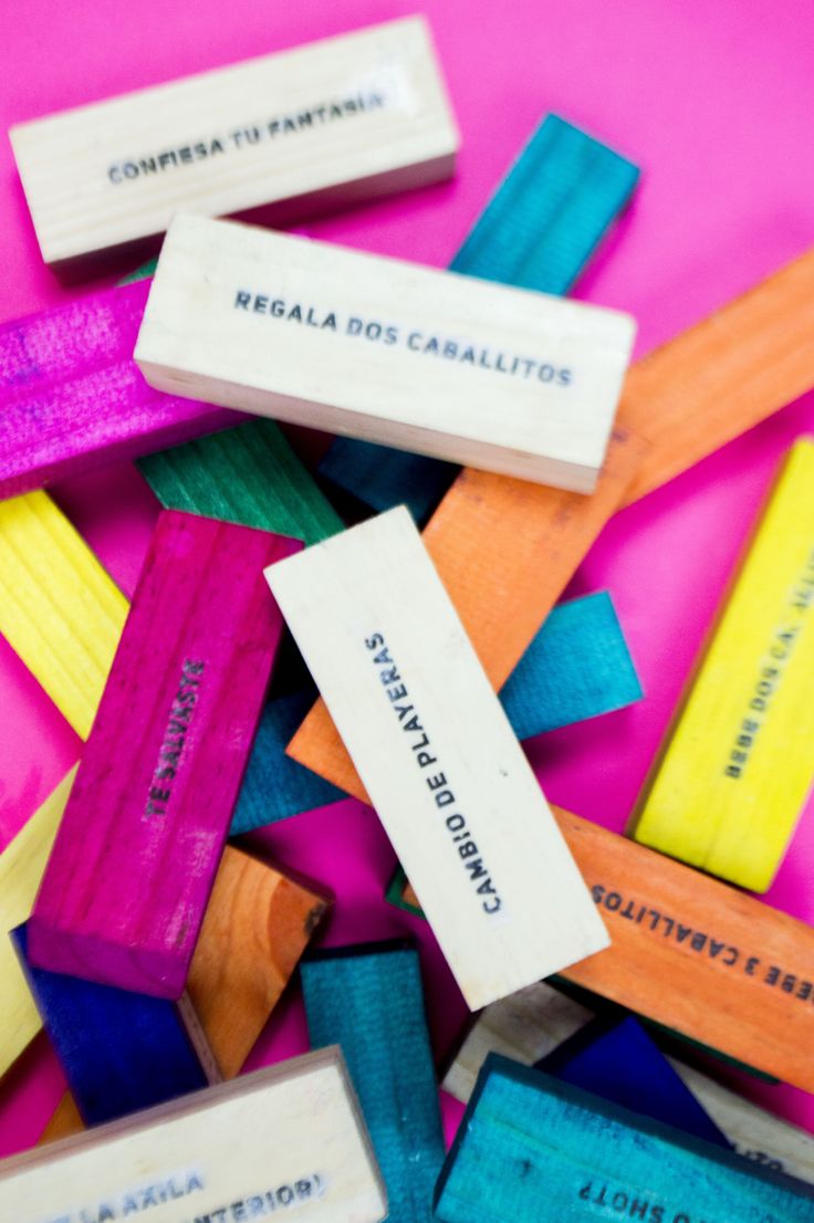 colorful wooden clothes pins sitting on top of a pink cloth covered ground with words written in spanish