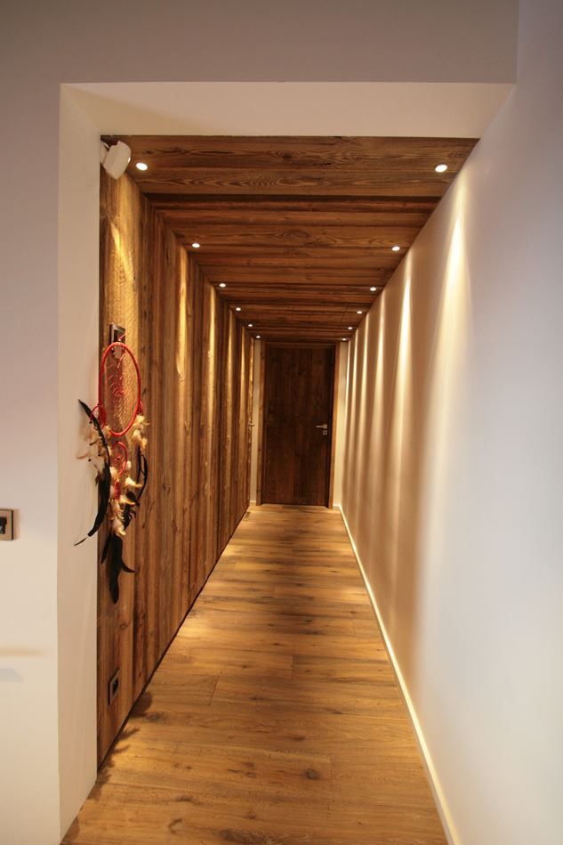 the hallway is lined with wood planks and has lights on either side of it