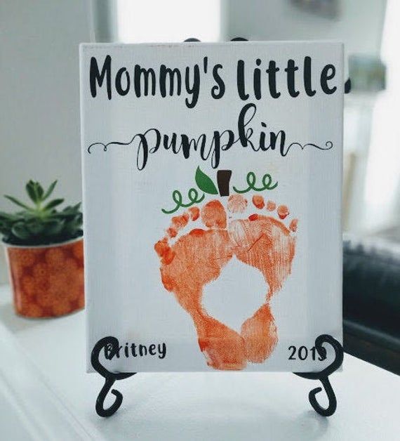 a sign that says mommy's little pumpkin feet on top of a table next to a potted plant