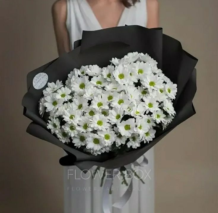 a woman holding a bouquet of white daisies