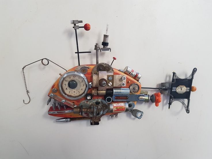 a clock made out of assorted objects on a white wall with wires and screws