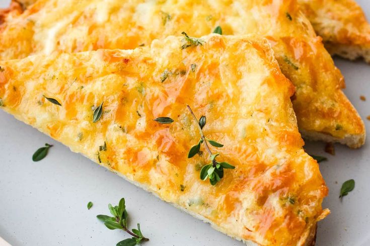 two pieces of cheesy pizza on a plate with parsley sprigs