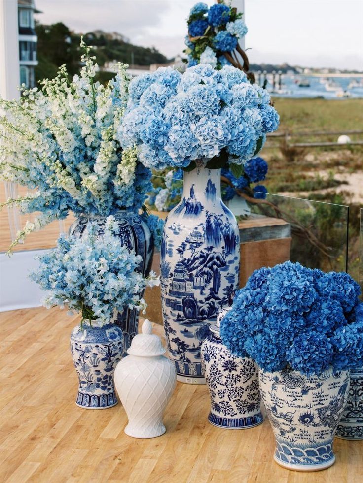 blue and white vases with flowers in them on a table