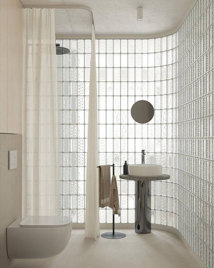 a bathroom with a sink, toilet and shower curtain in it's glass block wall