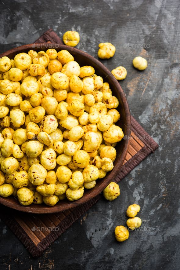 a wooden bowl filled with yellow chickpeas on top of a cloth covered table