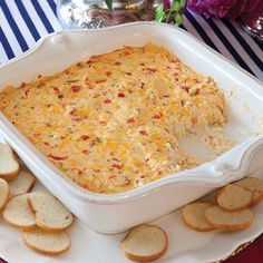 a casserole dish filled with cheese and crackers on a plate next to flowers