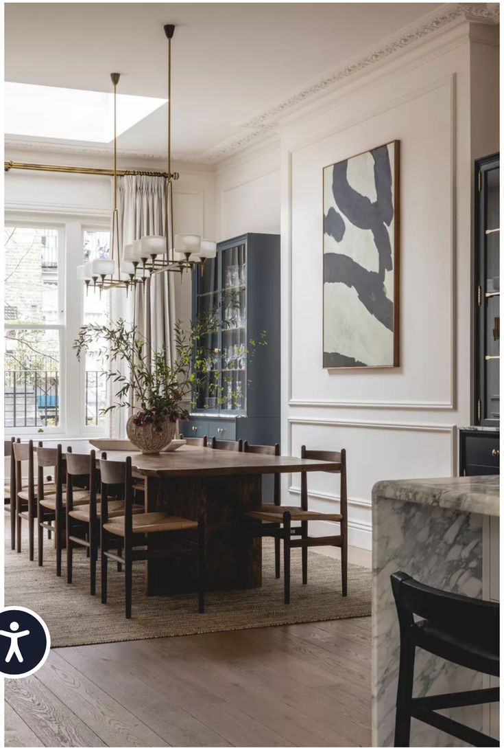 a dining room table and chairs in front of a large window with an abstract painting on the wall