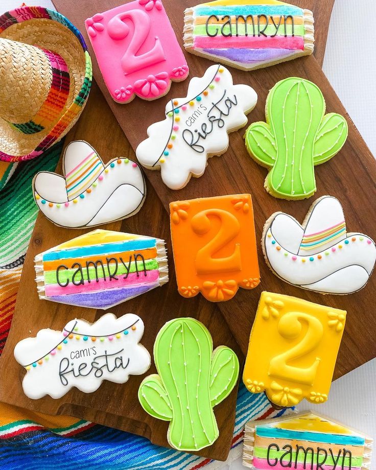 decorated cookies are arranged on a cutting board with the name candy written in different colors