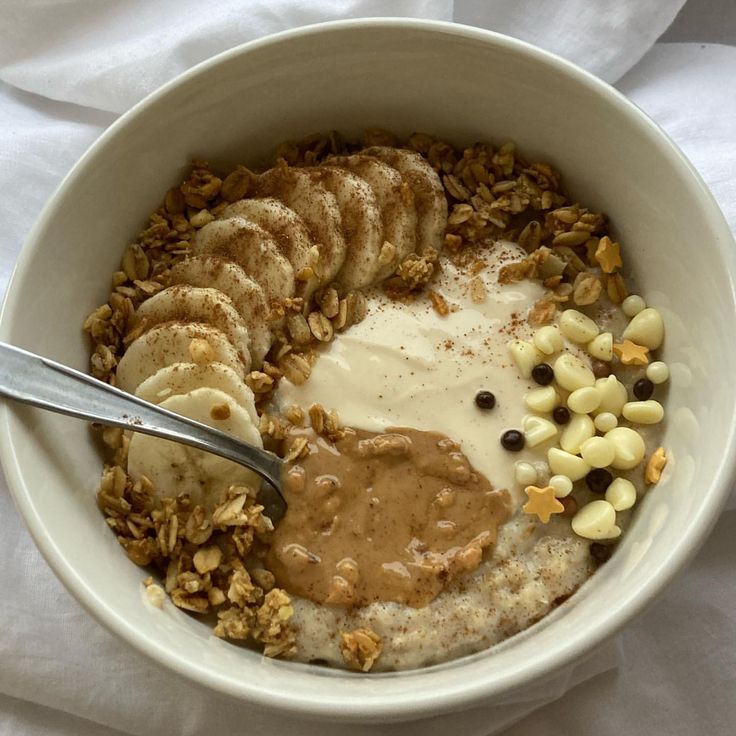 a bowl filled with oatmeal, bananas and other toppings next to a spoon