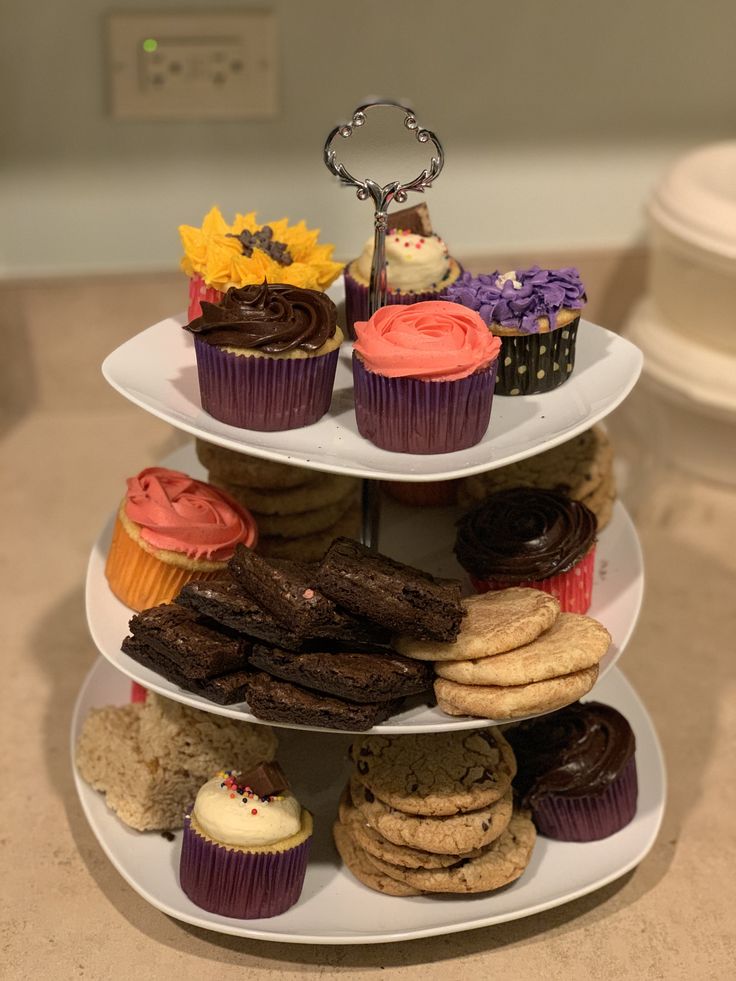 three tiered tray with cupcakes, cookies and muffins on it