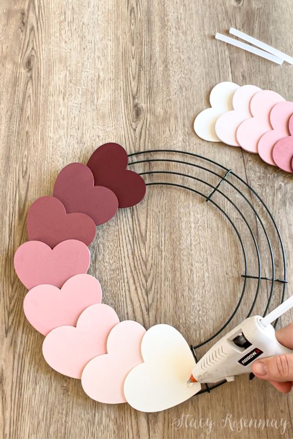 someone is making a heart wreath out of paper hearts on a wooden table with glue