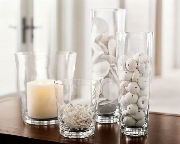 three clear vases filled with white balls and candles