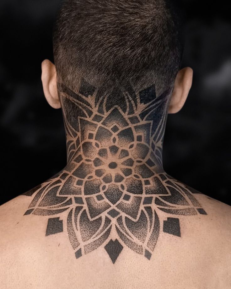 the back of a man's neck with an intricate tattoo design on his neck