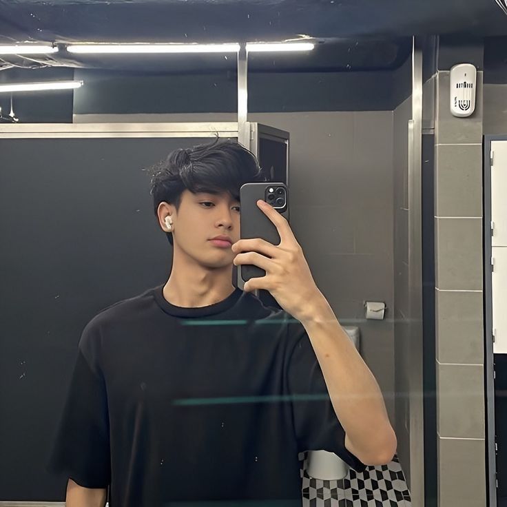 a young man taking a selfie in front of a mirror with his cell phone