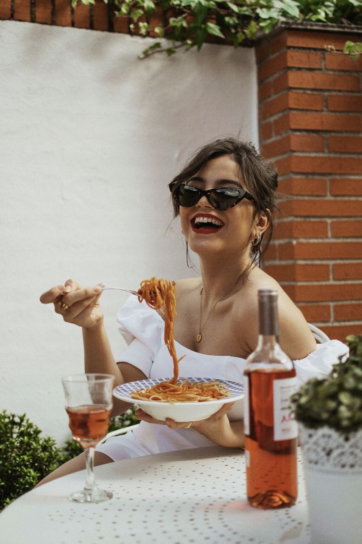 a woman sitting at a table eating spaghetti