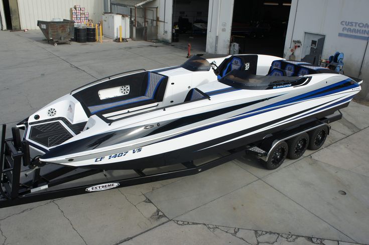 a white and blue speed boat parked in front of a building with another boat behind it