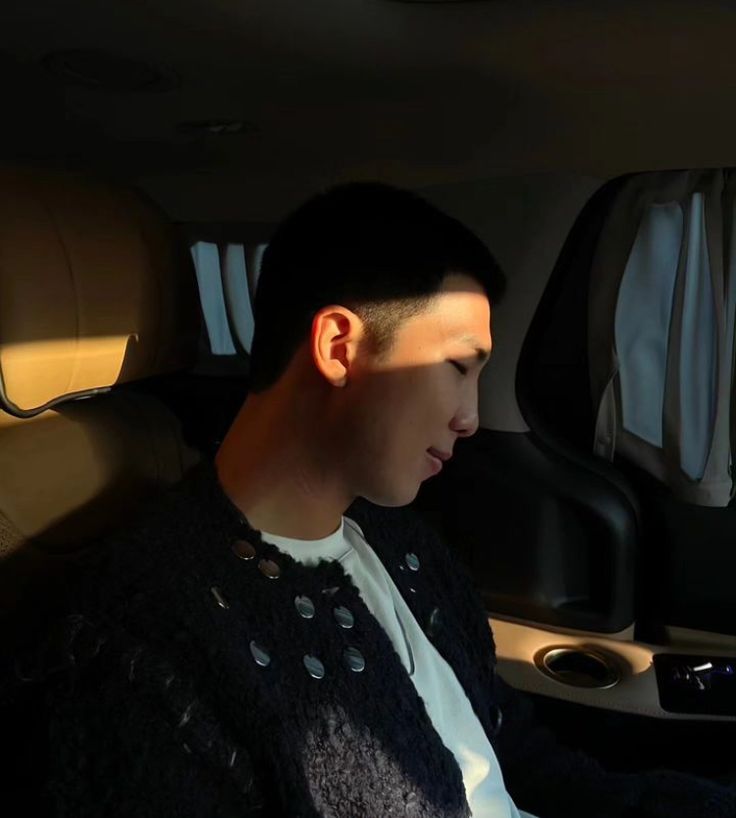 a young man sitting in the back seat of a car looking at his cell phone