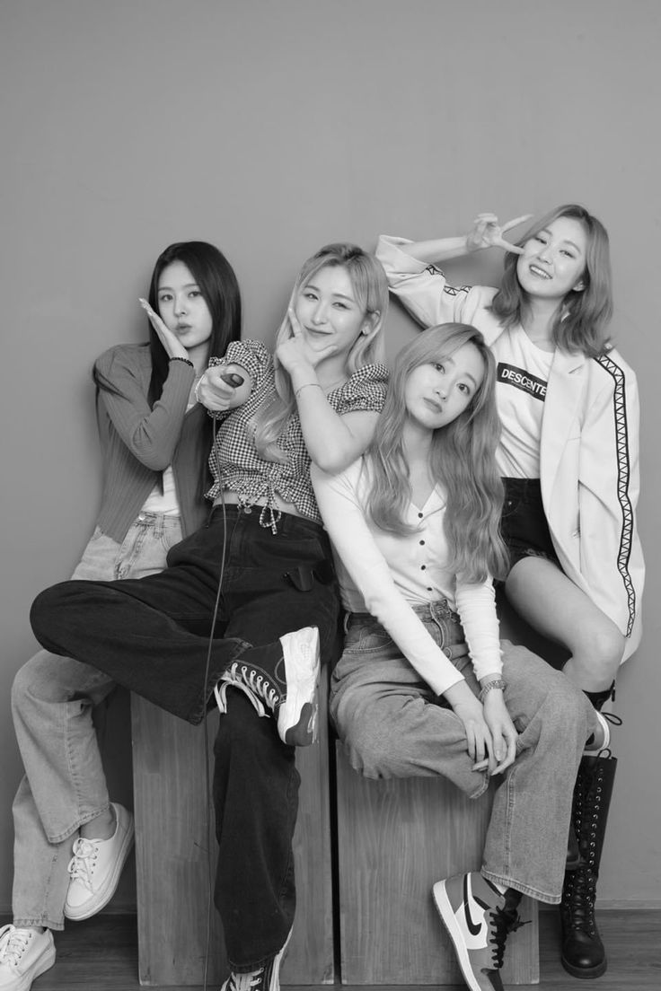 black and white photograph of four young women sitting on a bench with their hands in their hair