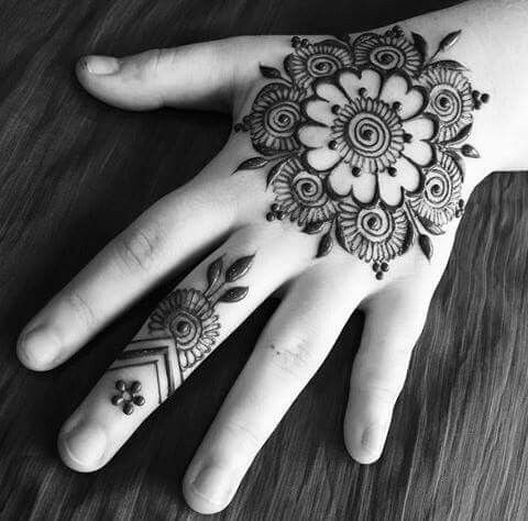 a woman's hand with hennap on it and an intricate flower design