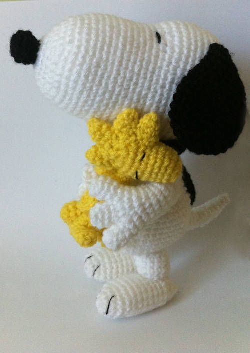 there is a knitted stuffed animal that looks like a dog with two small yellow flowers on its neck