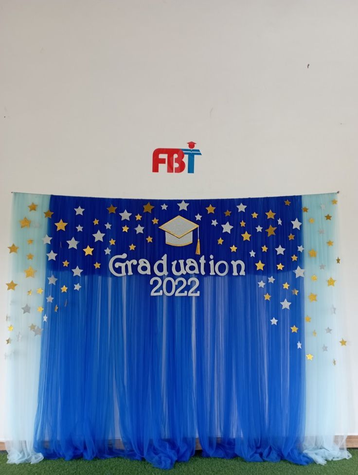 the graduation backdrop is decorated with stars and blue tulle for an event or celebration