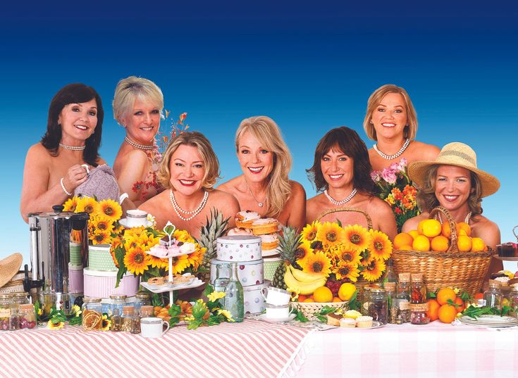 a group of women standing next to each other in front of a table covered with sunflowers