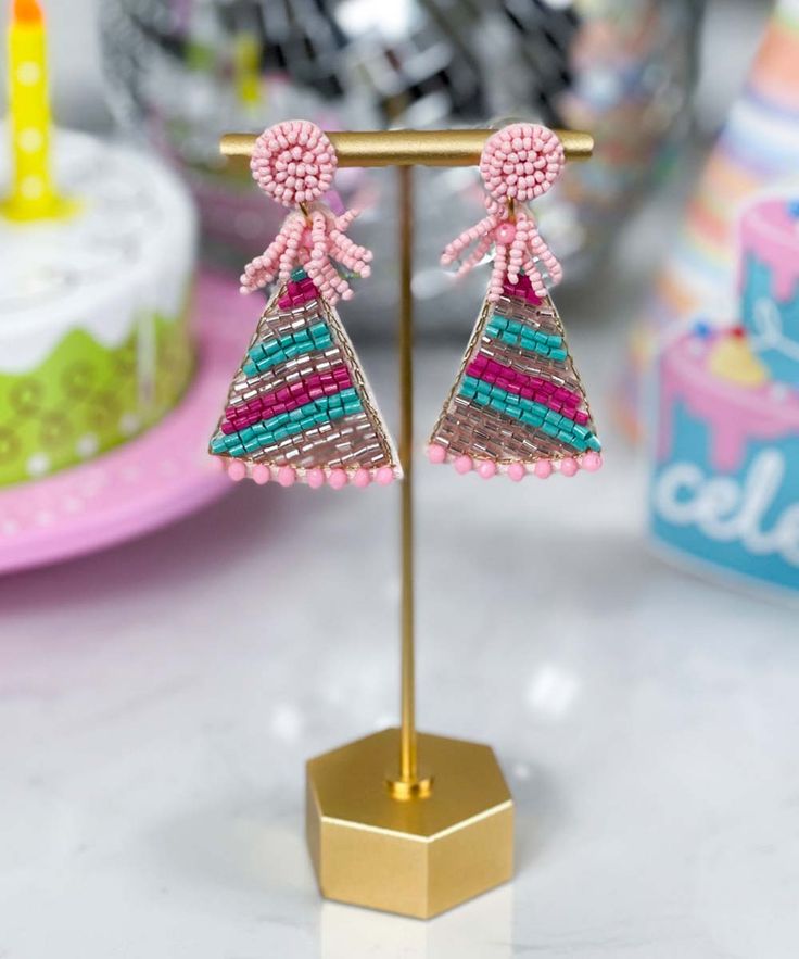 a pair of pink and blue beaded earrings on a stand