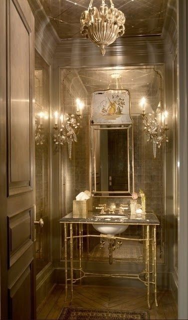 an image of a bathroom setting with chandelier and vanity in gold color scheme