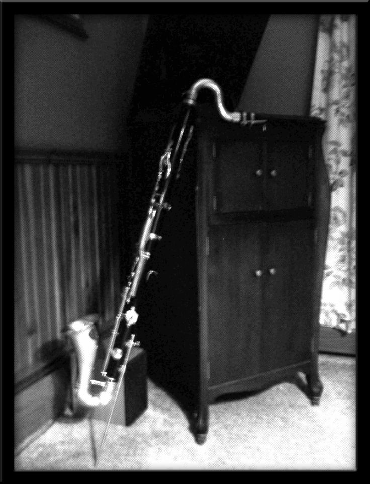 a black and white photo of a musical instrument leaning against a dresser in a bedroom