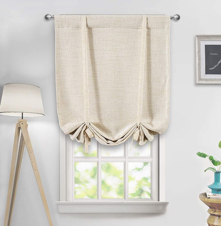 a window with a curtain hanging on the side of it and a lamp next to it