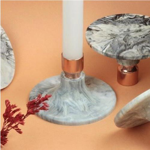 two marble candlesticks with one candle in the middle and another on the other